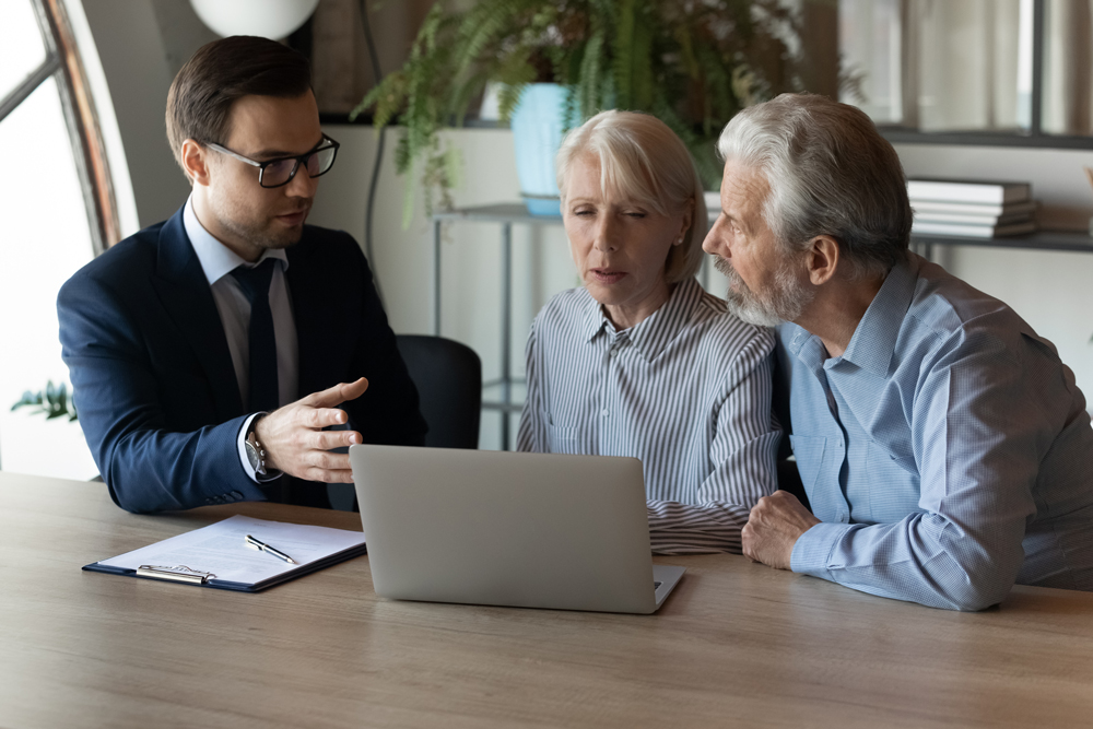 Older couple sitting in front of a laptop with a younger gentlemen in a suit